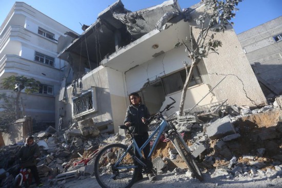 2月21日，在加沙地带南部城市拉法，巴勒斯坦少年经过以军空袭后的废墟。新华社发（哈立德·奥马尔摄）