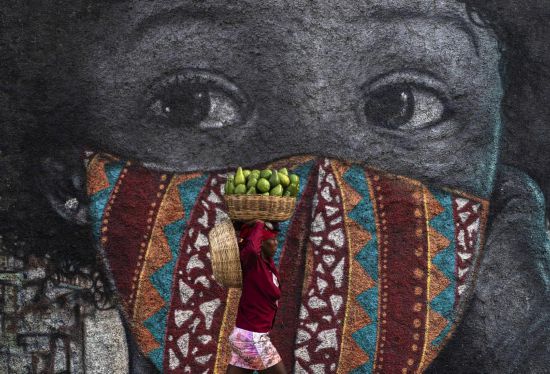 2021年8月24日，一名女子头顶水果走在海地太子港街头。新华社发（戴维·德拉帕斯摄）