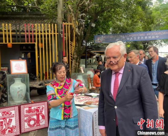 6月1日，拉法兰(右)在成都参访文化艺术园区，剪纸非遗传承人现场为他制作侧影剪纸。记者岳依桐摄