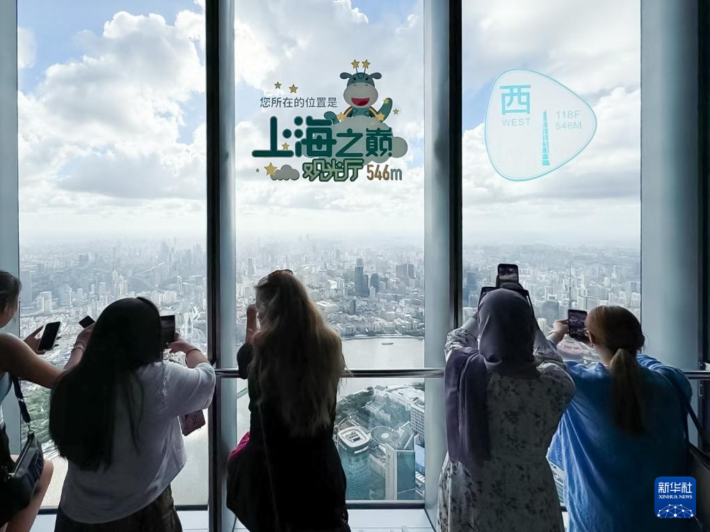 7月24日，外国网红在上海中心大厦观光层拍摄窗外的上海城市风光。新华社记者 黄安琪 摄